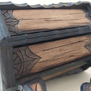May include: A wooden mug with a dark brown stain and intricate carvings. The mug has a handle and a base with carved feet. The mug is made of wood and has a rustic look.