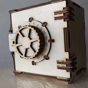 May include: A wooden toy safe with a combination lock. The safe is painted white and has a brown wooden dial with numbers 1 through 12. The safe has a small handle on the side.
