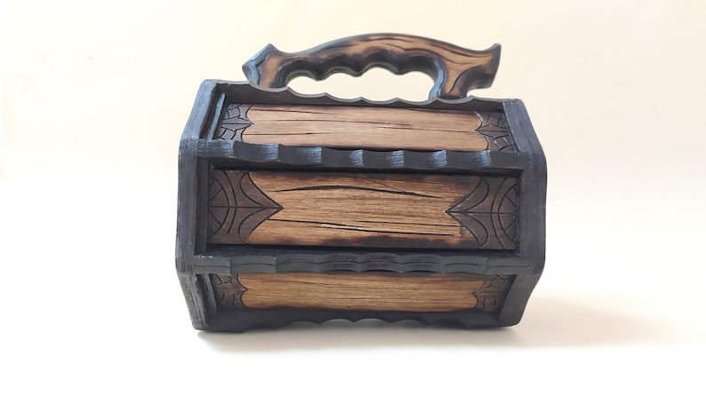 May include: A wooden box with a carved handle and intricate designs. The box is made of dark wood with a light wood interior.