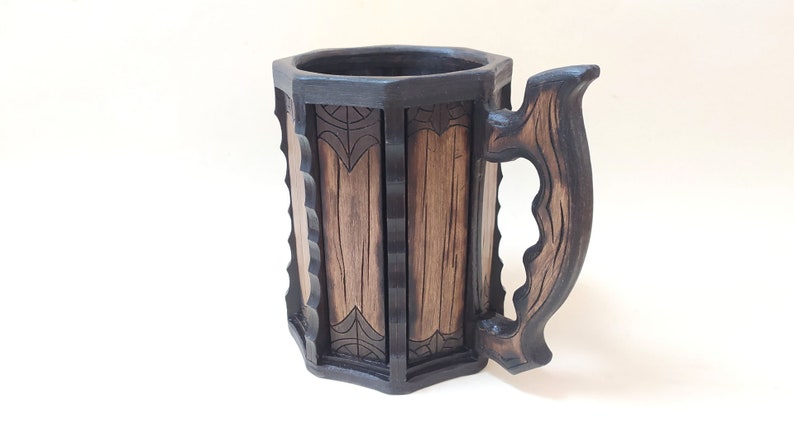 May include: A wooden beer stein with a dark brown finish and intricate carvings. The stein has a large handle and a wide mouth.
