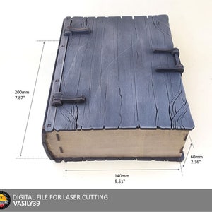 Puede incluir: Una caja de madera con tapa abatible y cierres metálicos. La caja mide 20 cm de alto, 14 cm de ancho y 6 cm de profundidad. La caja está hecha de madera y tiene un acabado gris oscuro.