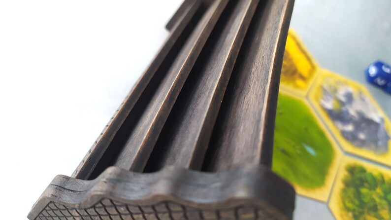 May include: Close-up of a wooden game piece with a grooved top and a textured bottom. The piece is dark brown and appears to be part of a board game.