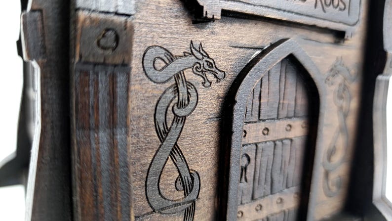 May include: A dark brown wooden structure featuring an arched door with vertical planks and a keyhole. The exterior surface is decorated with an engraved dragon design that wraps around the door frame. The wood grain is visible throughout.