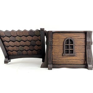 May include: A brown wooden-style box with a hinged lid that features a textured shingle pattern. The main body of the box has a horizontal wood grain texture and a small, arched window frame detail on the side, finished in dark brown tones.