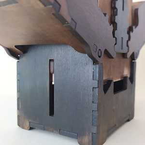 May include: A dark brown wooden box with a hinged lid. The box is made of multiple pieces of wood that are joined together with a dovetail joint. The box has a small opening on the side.