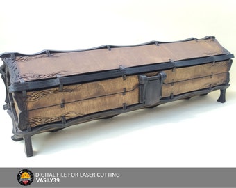 Puede incluir: Una caja de madera con tapa abatible y tallas decorativas. La caja es marrón con detalles negros y tiene un cierre de metal. La caja está sobre una superficie blanca.