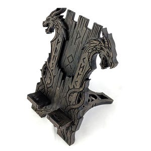 May include: A dark brown wooden phone stand featuring two dragon heads and intricate carvings. The stand has a unique design with a slot for a phone and a base for stability. The stand measures approximately 8 inches tall.