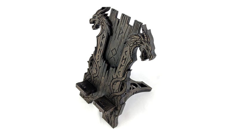 May include: A dark brown wooden phone stand featuring two dragon heads and intricate carvings. The stand has a unique design with a slot for a phone and a base for stability. The stand measures approximately 8 inches tall.