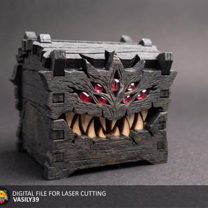 Könnte beinhalten: Eine dunkle, texturierte Holztruhe mit monsterartigem Design, die mehrere rote Edelsteinaugen und einen breiten, gezackten Mund voller scharfer, heller Zähne aufweist. Der Text unten lautet: DIGITAL FILE FOR LASER CUTTING VASILY39.
