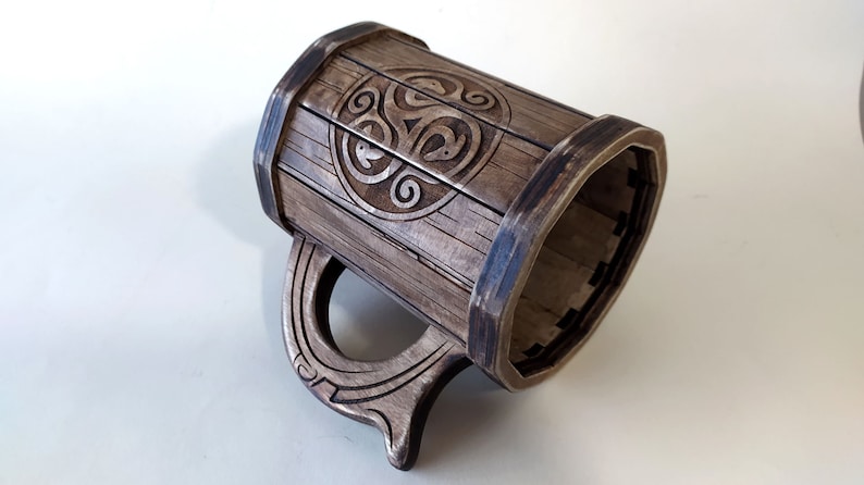 May include: A wooden beer stein with a Celtic knot design. The stein is brown and has a handle.