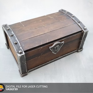 Può includere: Uno scrigno del tesoro in legno con dettagli in metallo e una fibbia in metallo decorativa. Lo scrigno è chiuso e ha una finitura in legno invecchiato.