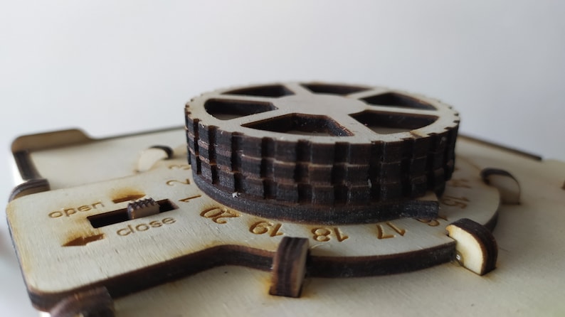 May include: A wooden box with a round dial and a sliding switch labelled "open" and "close". The dial has numbers from 1 to 20.