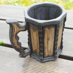 May include: A wooden beer stein with a dark brown finish and a carved handle. The stein has a hexagonal shape and is decorated with intricate carvings.