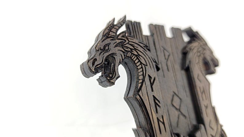 May include: A dark wooden dragon-themed decorative item. The dragon's head is intricately carved with open mouth and detailed features. The item has a castle-like structure with engraved runes. The overall design is a blend of fantasy and craftsmanship.