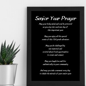 May include: A black framed print with a white background and the text "Senior Year Prayer" in a decorative font. The text continues with a prayer for a senior year filled with joy, challenges, and opportunities to connect with others.