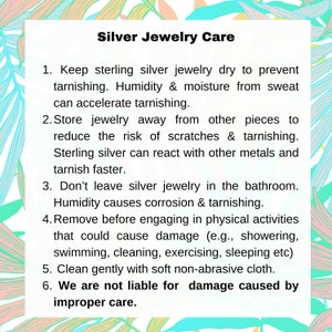 May include: White card with text "Silver Jewelry Care" and care instructions for sterling silver jewelry. Includes tips on preventing tarnish, storing jewelry, and cleaning. The background has a colorful tropical leaf design.