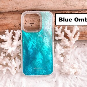 May include: A clear phone case with a blue ombre design. The case has a white border and the text "beach vibes hawaii" printed on the back.