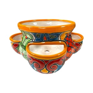 May include: A colorful ceramic planter with multiple compartments. The planter features a vibrant design with orange, red, blue, and green accents. The design includes floral and geometric patterns. The planter is suitable for growing multiple plants.