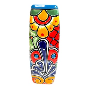 May include: A tall, hand-painted ceramic vase with a vibrant floral design. The vase features a rectangular shape with a blue rim and is adorned with colorful patterns in red, yellow, green, and blue. The vase is approximately 8 inches tall.