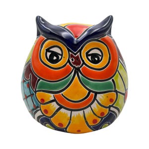 May include: A colorful ceramic owl figurine. The owl features a vibrant design with orange, yellow, green, and blue hues. The owl's eyes are large and round, and it has a small beak. The owl's wings are decorated with intricate patterns.