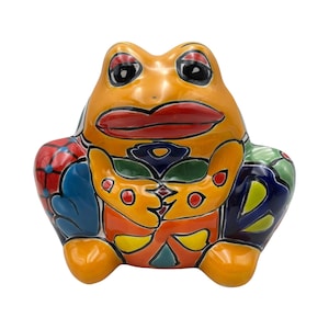 May include: A ceramic frog figurine with a vibrant, hand-painted design. The frog features a bright orange body, red lips, and large black eyes. Its belly and sides are adorned with colorful patterns in blue, green, yellow, and orange. A decorative piece.