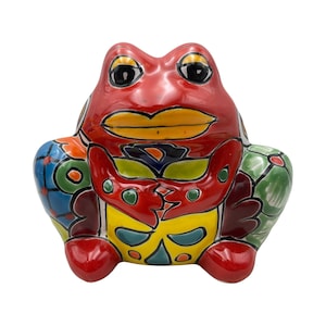 May include: A ceramic frog figurine with a vibrant, hand-painted design. The frog features a red body, yellow accents, and colorful patterns on its legs and back. The figurine is a decorative item.