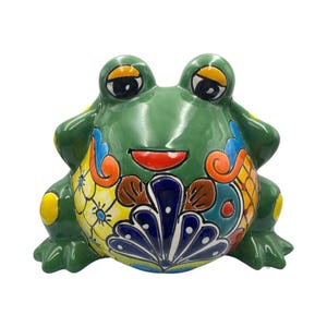 May include: A ceramic frog figurine in a vibrant green hue, adorned with colorful floral and geometric patterns. The frog has large, expressive eyes, a red mouth, and yellow accents. The design incorporates blue, orange, and yellow details, creating a cheerful aesthetic.