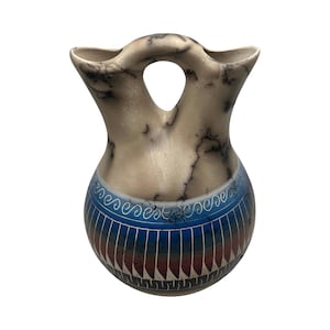 May include: A ceramic vessel with a double-spout bridge handle design. The upper portion is cream-colored with black smoke-fire markings. The lower bulbous section features a blue, red, and black gradient with white geometric line patterns.