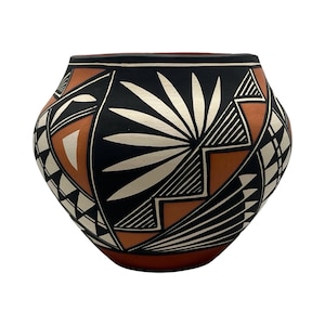 May include: A rounded ceramic pot featuring a matte terracotta base color decorated with intricate geometric patterns in black and white. The design includes a central sunburst motif, jagged stepped lines, and triangular shapes encircling the body.