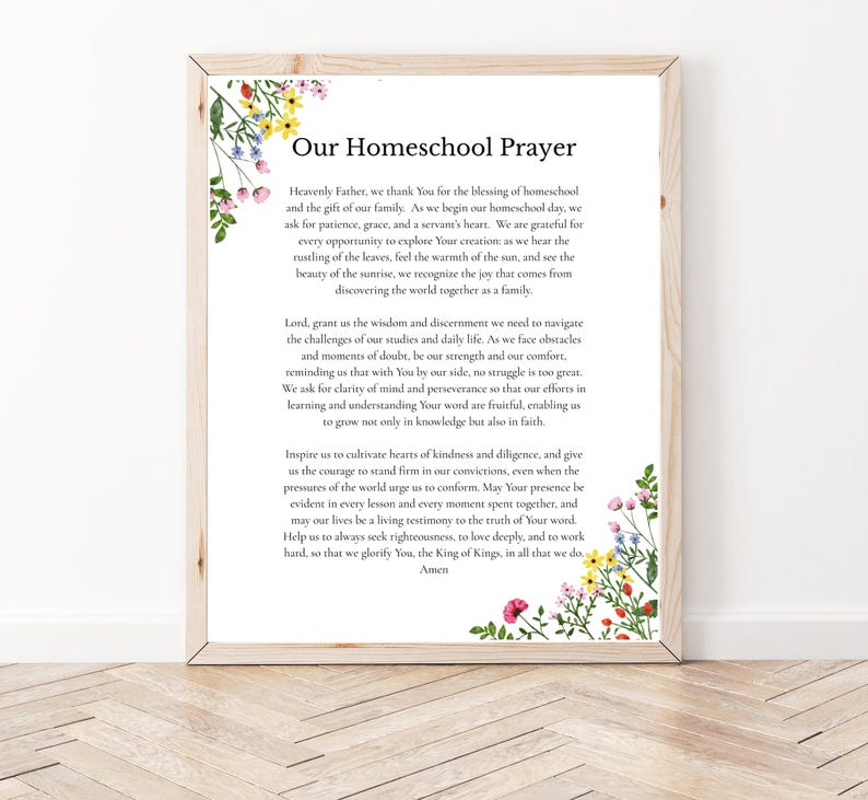 May include: A framed wall art print titled Our Homeschool Prayer, featuring black text on a white background. The design is decorated with watercolor illustrations of colorful wildflowers in the top left and bottom right corners, set in a light wood frame.