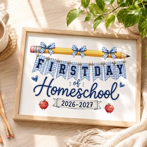 May include: A framed print featuring a yellow pencil with three blue gingham bows, a banner with the text FIRST DAY OF HOMESCHOOL, two small red apple illustrations with faces, and the text 2026-2027 on a banner at the bottom of the white paper.
