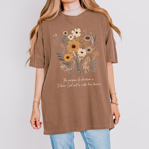 May include: A brown oversized t-shirt with a floral design and the text "The purpose of education is to know God and to make him known."