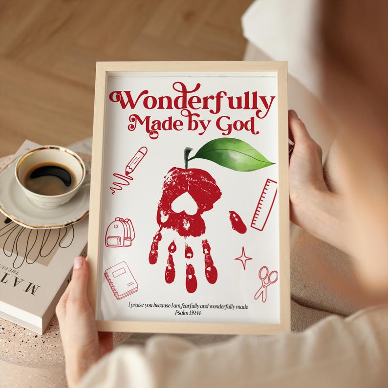 May include: A framed print featuring the red text Wonderfully Made by God at the top and the verse I praise you because I am fearfully and wonderfully made Psalm 139:14 at the bottom. The center shows a red handprint apple with a green leaf.