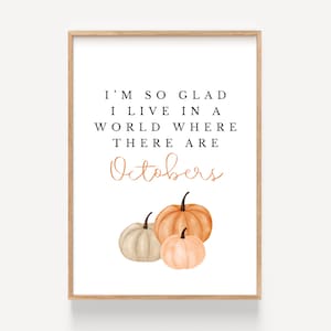 May include: A white printable art print with a quote about October. The quote reads "I'm so glad I live in a world where there are Octobers." The print features three watercolor pumpkins in shades of orange and beige.