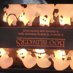 May include: A string of 10 white ghost-shaped lights with glowing faces. The lights are on a black background with the text "BOO BLINKERS" and "A strand of 10 blinking Halloween lights to decorate your favorite haunt!"  $15.95