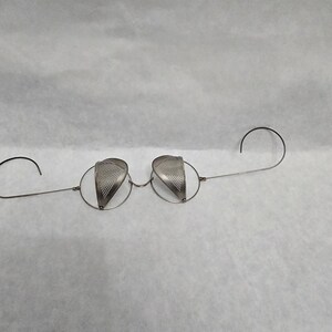 May include: A pair of antique silver-toned spectacles with perforated eye shields. The glasses have a delicate wire frame and curved temples for securing them over the ears. The eye shields are shaped like teardrops.