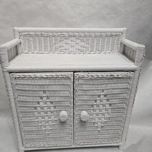 May include: A white wicker cabinet with two doors and a small bench seat. The cabinet features diamond-shaped woven patterns on the doors and round knobs. The piece is painted in a solid white color.