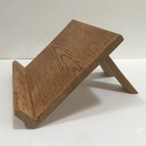 Könnte beinhalten: Ein Bücherständer aus hellem Eichenholz mit schlichtem Design. Der Ständer ist angewinkelt, um ein Buch oder Tablet zu halten.