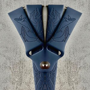 K&ouml;nnte beinhalten: Ein dunkelblaues Silikon-Armband mit einem Wal-Design. Das Armband hat eine Metallschlie&szlig;e und eine strukturierte Oberfl&auml;che.