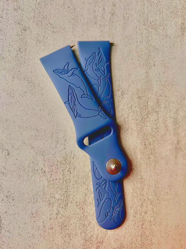 K&ouml;nnte beinhalten: Ein blaues Silikon-Armband mit einem Wal-Design. Das Armband ist aus weichem, bequemem Silikon gefertigt und verf&uuml;gt &uuml;ber ein detailliertes Wal-Design.