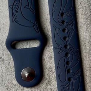 K&ouml;nnte beinhalten: Ein dunkelblaues Silikon-Armband mit einem Wal-Design. Das Armband hat eine strukturierte Oberfl&auml;che und einen Schlie&szlig;enverschluss.