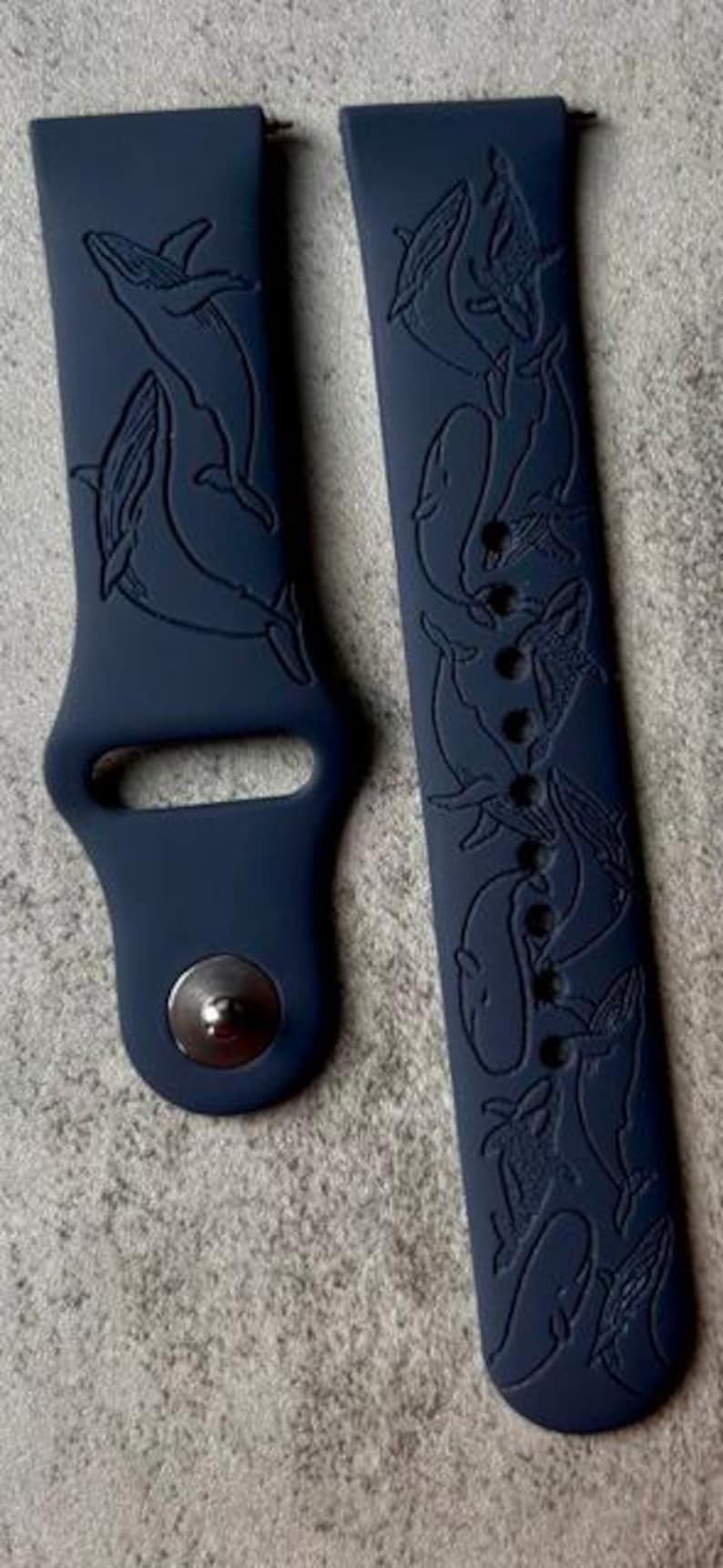 K&ouml;nnte beinhalten: Ein dunkelblaues Silikon-Armband mit einem Wal-Design. Das Armband hat eine strukturierte Oberfl&auml;che und einen Schlie&szlig;enverschluss.