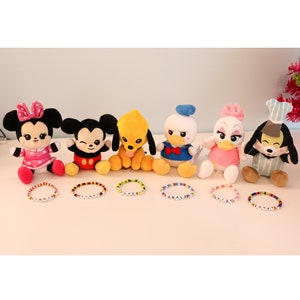 以下が含まれることがあります： ディズニーキャラクターのぬいぐるみ7体と、それぞれの名前を綴ったカラフルなビーズブレスレット。ウィニー、ミッキー、プルート、ドナルド、デイジー、グーフィーです。