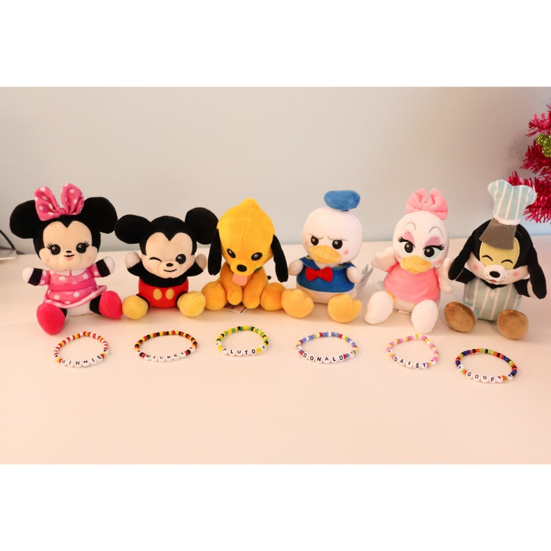 以下が含まれることがあります： ディズニーキャラクターのぬいぐるみ7体と、それぞれの名前を綴ったカラフルなビーズブレスレット。ウィニー、ミッキー、プルート、ドナルド、デイジー、グーフィーです。