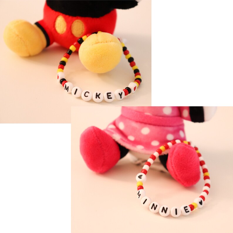 以下が含まれることがあります： ミッキーマウスとミニーマウスのぬいぐるみ2体と、名前が書かれたビーズのブレスレット。ミッキーのブレスレットは赤、黄、黒で、ミニーのブレスレットは赤、黄、白です。
