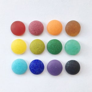 May include: Twelve round, smooth, colourful glass stones in various shades of red, orange, yellow, green, blue, purple, and brown.