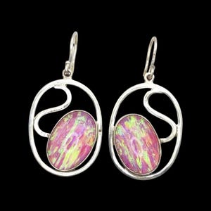 Può includere: Un paio di orecchini pendenti ovali color argento. Ogni orecchino presenta una vivace pietra ovale con sfumature rosa, gialle e viola, incastonata in una cornice traforata decorativa. Chiusura a gancio semplice.