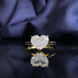 Pode incluir: Um anel de ouro com um grande diamante em forma de coração. O diamante é claro e brilhante.