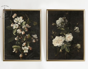 May include: Two framed botanical prints featuring white flowers on a dark background. The print on the left features a cluster of white apple blossoms, while the print on the right features a bouquet of white roses.