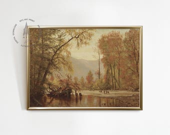 May include: A framed landscape painting depicting a river scene with trees in autumn colors. The artwork features a gold frame and a serene view of a river, trees, and distant mountains. The painting has a vintage aesthetic.
